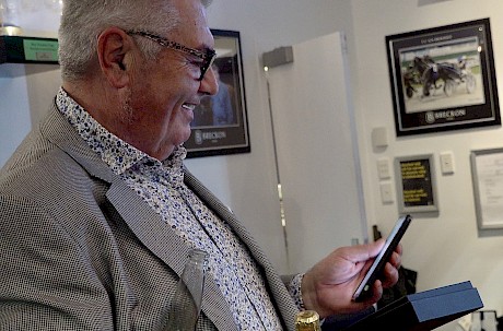 Trevor Casey has Melbourne owner Merv Butterworth on the phone as he accepts the trophies.